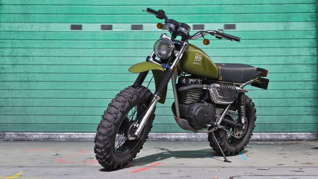The green Dinka Enduro motorcycle parked outside a garage